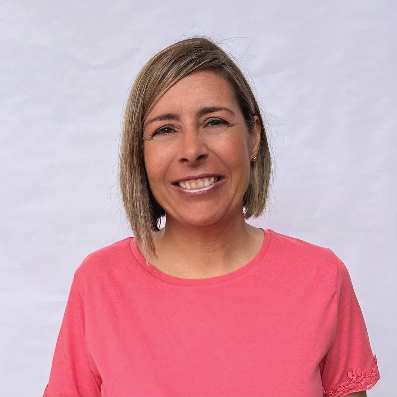 Mujer sonriendo con camiseta rosa, fondo blanco.