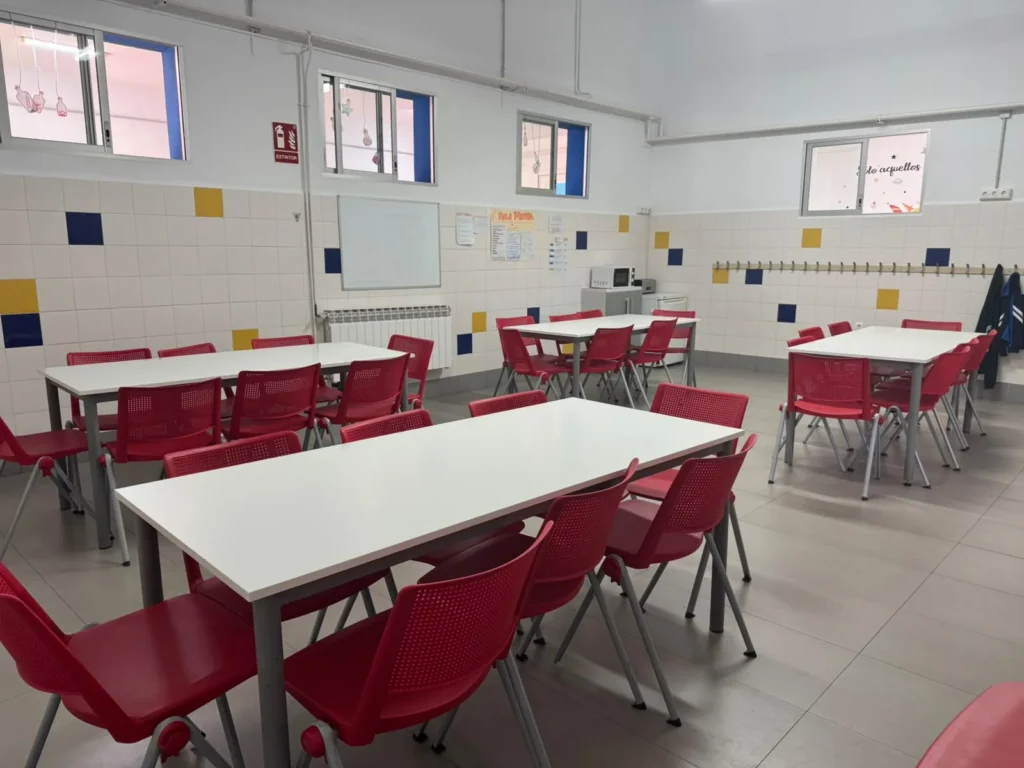 Comedor escolar de Juan XXIII Zaidín con mesas blancas y sillas rojas