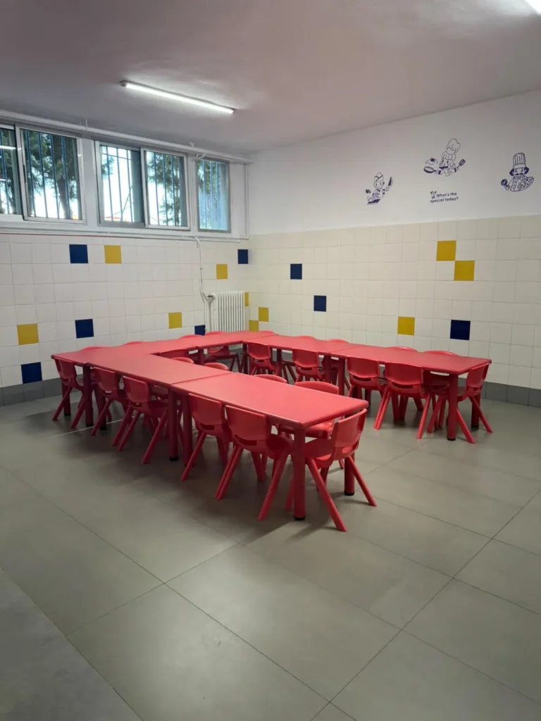 Zona de Infantil del comedor escolar, con mesas bajas y sillas rojas